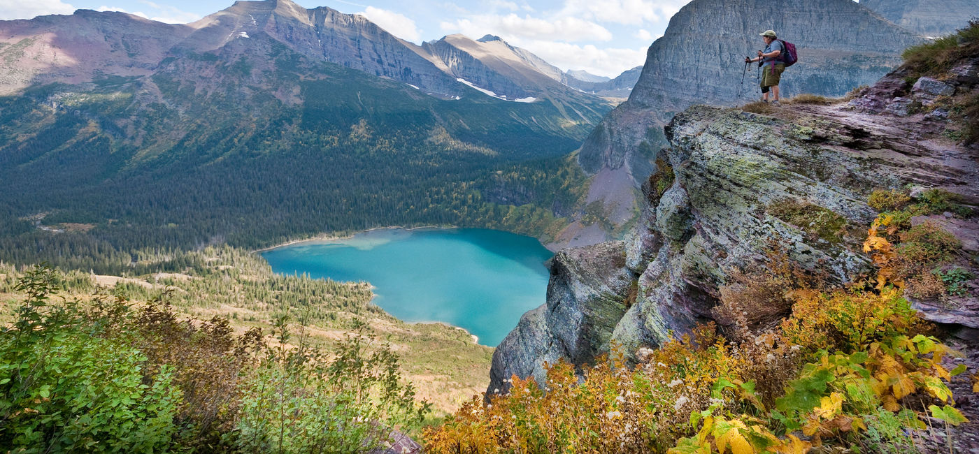 Image: PHOTO: Hiker looking out from the Grinnell Glacier Trail in Glacier National Park. (photo via JeffGoulden/E+)