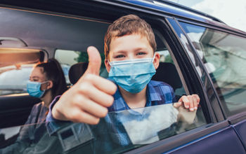 Passengers wearing masks in the backseat of a car.