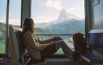 Young woman traveling on the train near Matterhorn, Swiss Alps