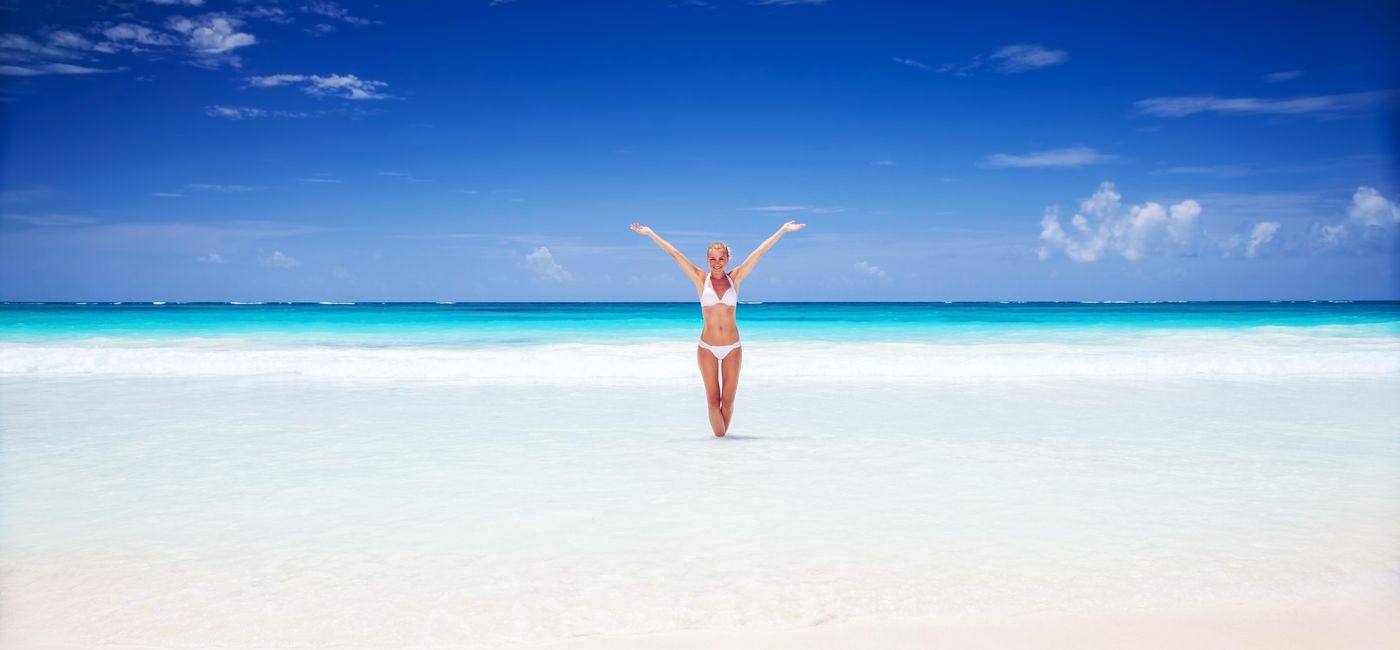 Image: PHOTO: Happy woman on the beach in Cancun, Mexico. (photo via Anna_Om/iStock/Getty Images Plus)