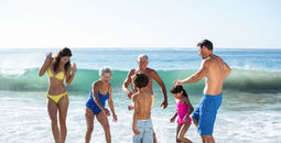 Multi-generational family group playing in the surf.