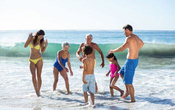Multi-generational family group playing in the surf.