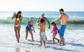 Multi-generational family group playing in the surf.