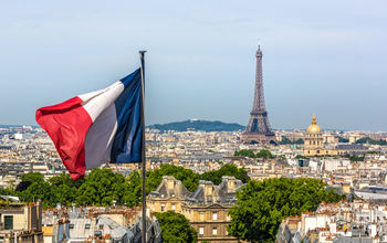 The French Flag waving with Paris and the Eiffel Tower in the background.