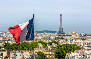 The French Flag waving with Paris and the Eiffel Tower in the background.