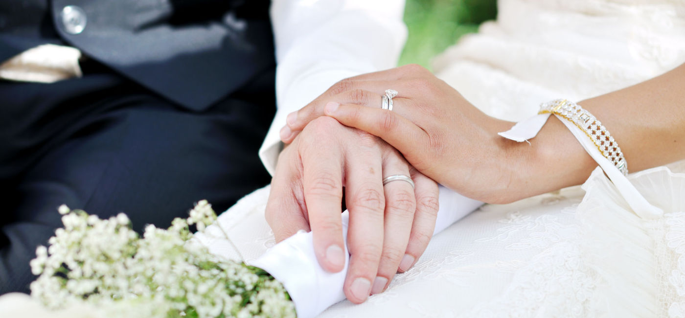 Image: A husband and wife holding hands on their wedding day. (Photo via iStock/Getty Images E+/Csondy)