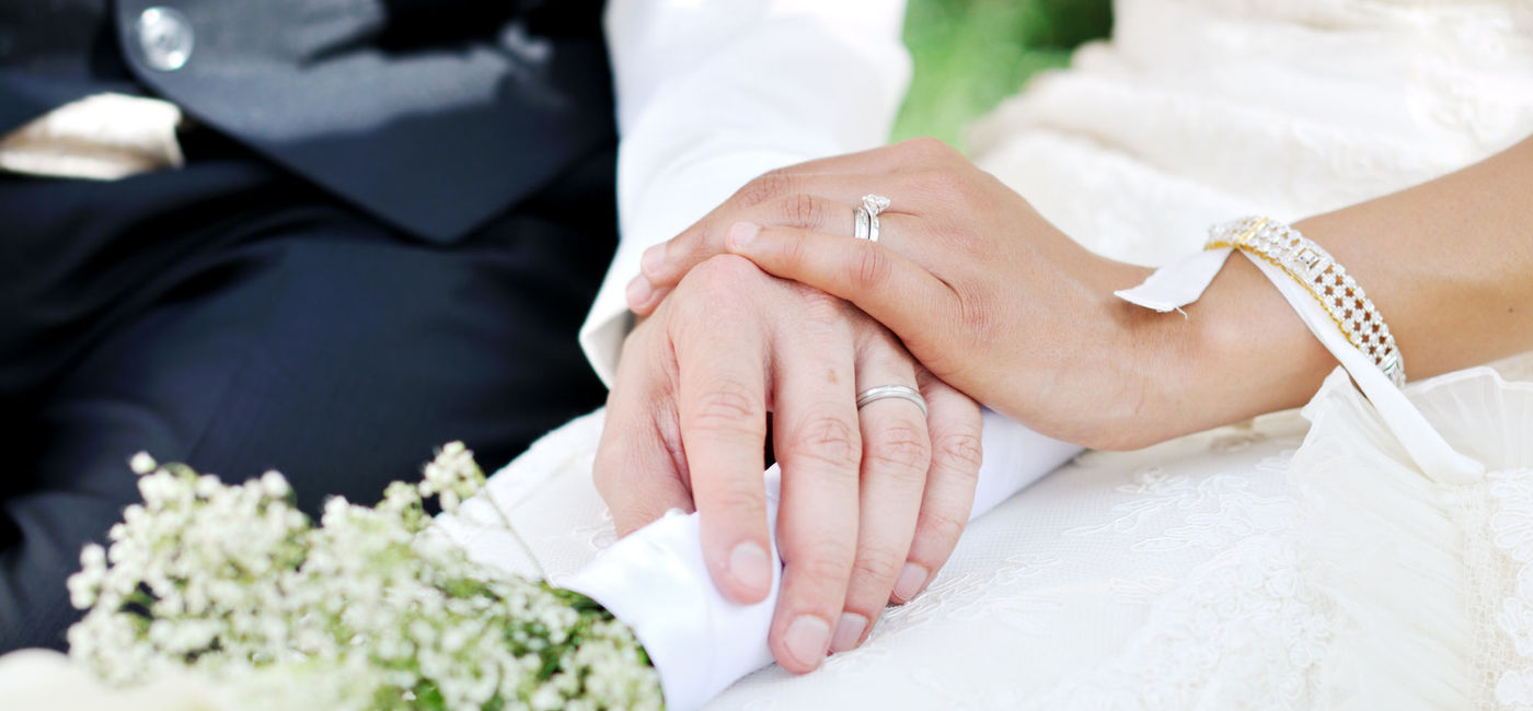 Image: A husband and wife holding hands on their wedding day. (Photo via iStock/Getty Images E+/Csondy)