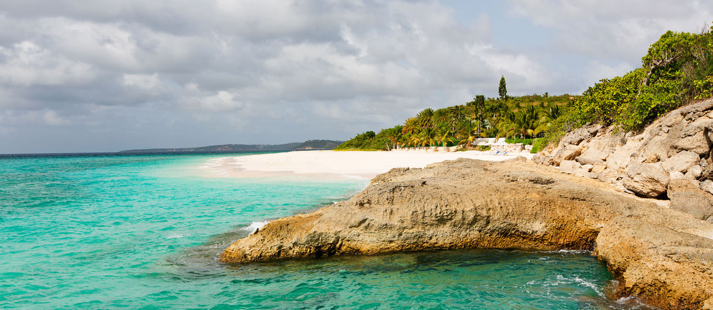 view at rugged rocky seashore and white sand empty beach at anguilla, island in caribbean sea (Photo via noblige / iStock / Getty Images Plus)