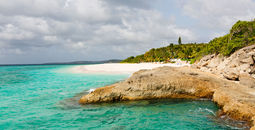 view at rugged rocky seashore and white sand empty beach at anguilla, island in caribbean sea (Photo via noblige / iStock / Getty Images Plus)