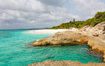 view at rugged rocky seashore and white sand empty beach at anguilla, island in caribbean sea (Photo via noblige / iStock / Getty Images Plus)