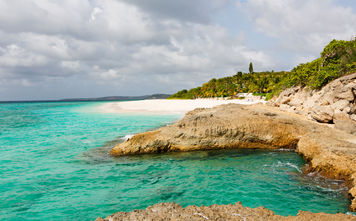 view at rugged rocky seashore and white sand empty beach at anguilla, island in caribbean sea (Photo via noblige / iStock / Getty Images Plus)
