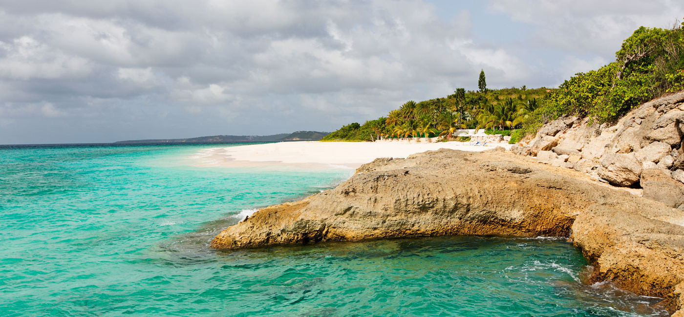 Image: view at rugged rocky seashore and white sand empty beach at anguilla, island in caribbean sea (Photo via noblige / iStock / Getty Images Plus)