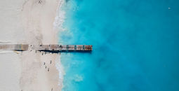 Drone photo of pier in Grace Bay, Providenciales, Turks and Caicos. The caribbean blue sea and white sandy beaches can be seen (photo via JoaoBarcelos / iStock / Getty Images Plus)