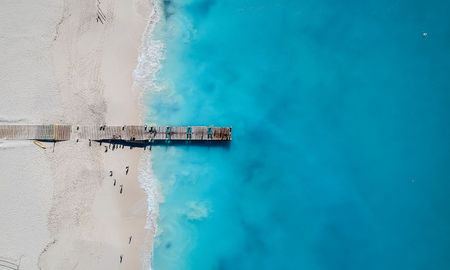 Drone photo of pier in Grace Bay, Providenciales, Turks and Caicos. The caribbean blue sea and white sandy beaches can be seen (photo via JoaoBarcelos / iStock / Getty Images Plus)