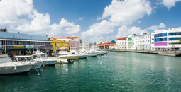Main water canal with ships and shops in Bridgetown, capital of Barbados. Caribbean (photo via Fyletto / iStock / Getty Images Plus)