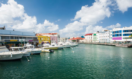 Main water canal with ships and shops in Bridgetown, capital of Barbados. Caribbean (photo via Fyletto / iStock / Getty Images Plus)