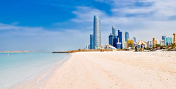 sunny beach and cityscape in Abu Dhabi, UAE (photo via vlarub/iStock/Getty Images Plus)