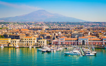 Beautiful view of Catania cruise port with smoking volcano Etna in the background. (Photo via  NAPA74 / iStock / Getty Images Plus)