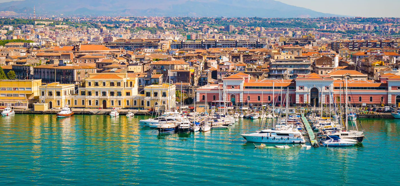 Image: PHOTO: Beautiful view of Catania cruise port with smoking volcano Etna in the background. (photo via NAPA74/iStock/Getty Images Plus) (NAPA74 / iStock / Getty Images Plus)