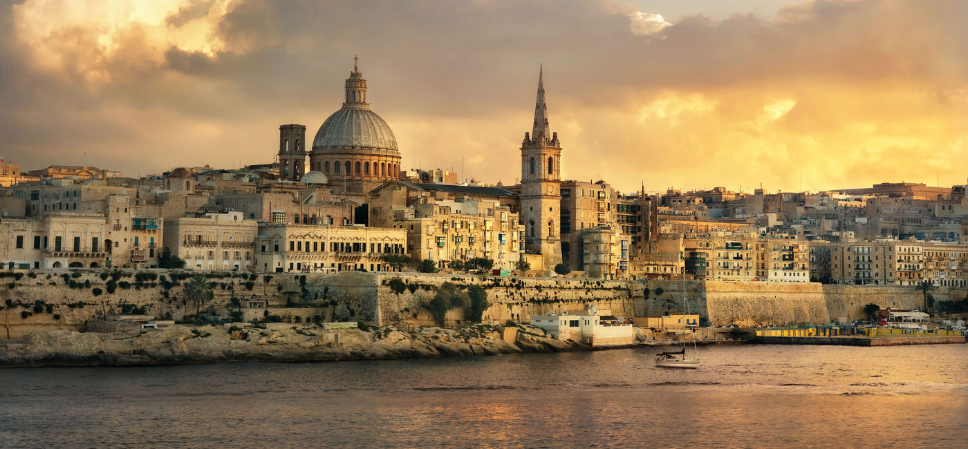 Image: anoramic view of Valletta at sunset with Carmelite Church dome and St. Pauls Anglican Cathedral. Malta (photo via Bareta / iStock / Getty Images Plus)