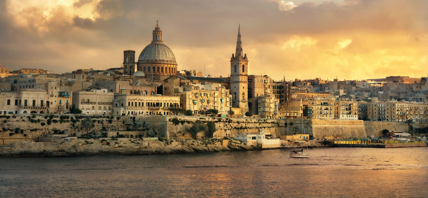 Image: anoramic view of Valletta at sunset with Carmelite Church dome and St. Pauls Anglican Cathedral. Malta (photo via Bareta / iStock / Getty Images Plus)