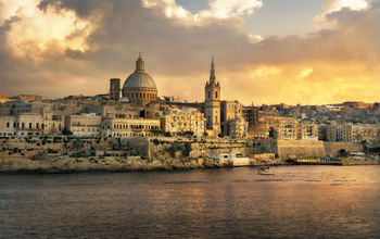 Panoramic view of Valletta at sunset with Carmelite Church dome and St. Pauls Anglican Cathedral. Malta (photo via Bareta / iStock / Getty Images Plus)