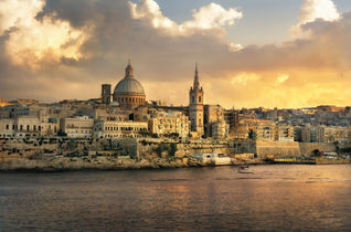 Panoramic view of Valletta at sunset with Carmelite Church dome and St. Pauls Anglican Cathedral. Malta (photo via Bareta / iStock / Getty Images Plus)
