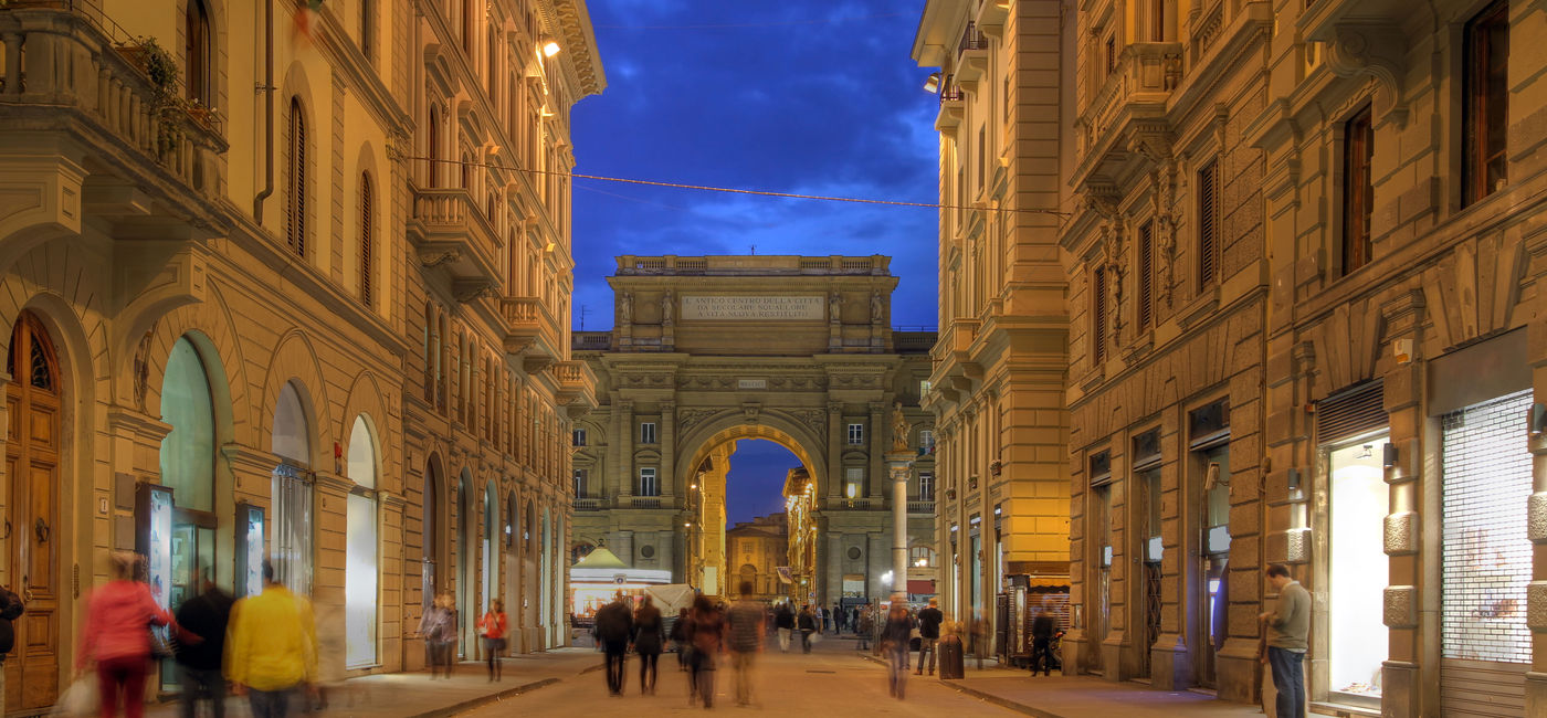 Image: Pedestrian street at night in downtown Florence, Tuscany, Italy. The street (Via degli Speziale) is leading towards the Republic Square (Piazza della Repubblica) with the Arch (Arcone) in the background. (photo via repistu / iStock / Getty Images Plus)