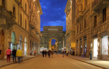 Pedestrian street at night in downtown Florence, Tuscany, Italy. The street (Via degli Speziale) is leading towards the Republic Square (Piazza della Repubblica) with the Arch (Arcone) in the background. (photo via repistu / iStock / Getty Images Plus)
