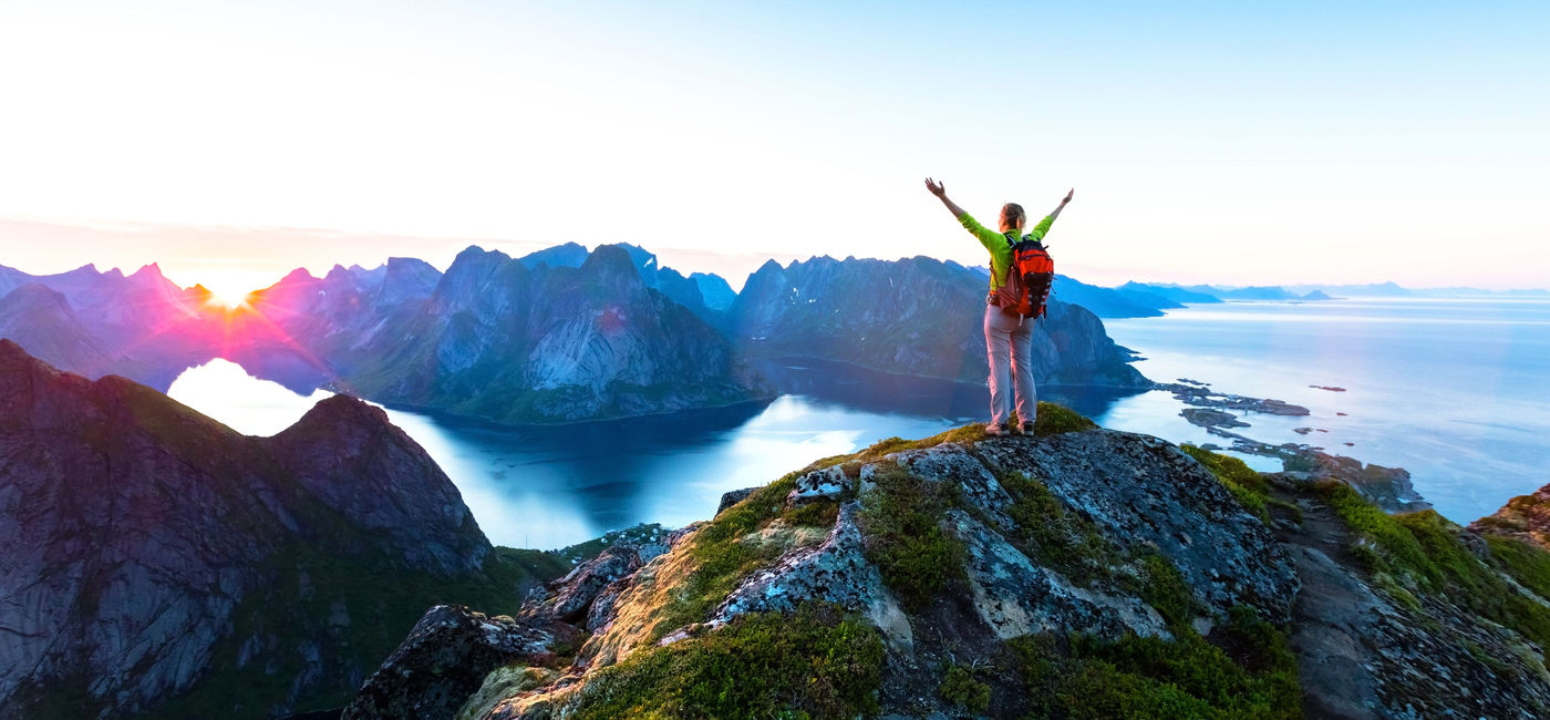 Image: PHOTO: Hiker enjoying a scenic view at the top of Reinebringen hike in the Lofoten archipelago in Norway. (NicoElNino / iStock / Getty Images Plus)
