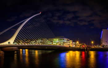 Panorama of Dublin by night. River with citylights reflections. Samuel Beckett Bridge. (photo via muzzyco / iStock / Getty Images Plus)