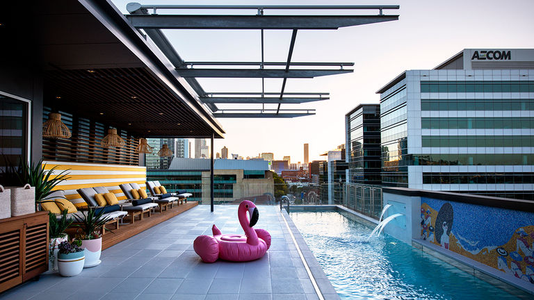 A rooftop pool features two-person loungers.