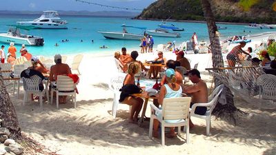 Many Caribbean beach bars, such as Soggy Dollar Bar in the British Virgin Islands, feature tables in the sand and ocean views.  // © 2017 British Virgin Islands Tourist Board