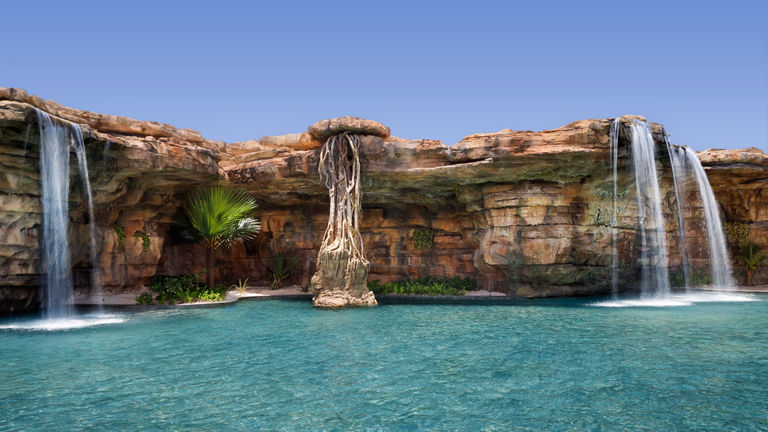Waterfalls flow into a cenote-inspired pool at Lopesan Caoba Lagoon.