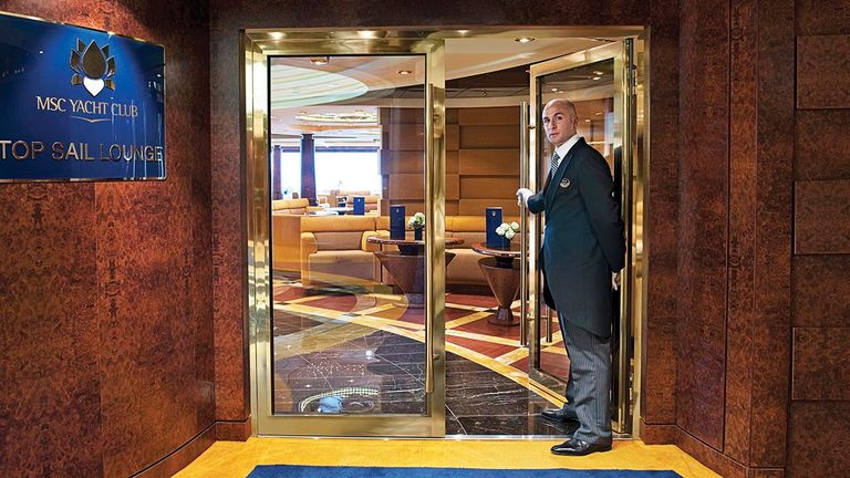 A butler welcomes guests to the MSC Yacht Club Top Sail Lounge.