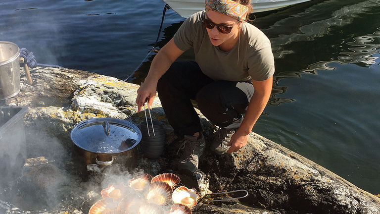 A guide demonstrates cooking seafood in the wild.