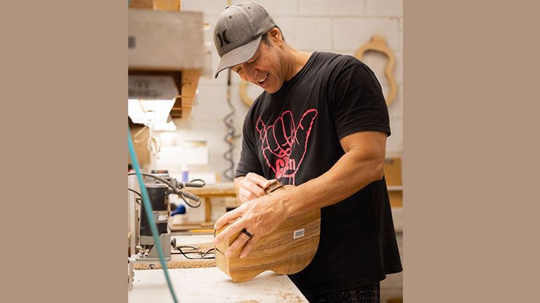 A worker finishes assembling the body of an ukulele at the Kanilea Ukulele factory.
