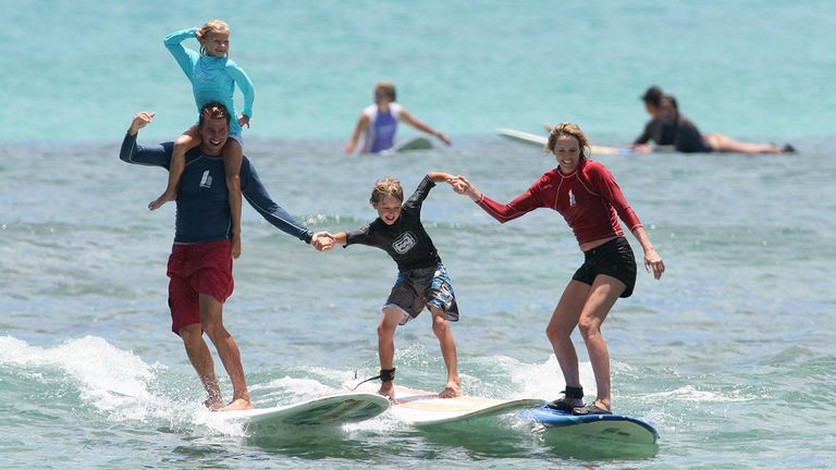 Families hang 10 together during a surfing lesson.