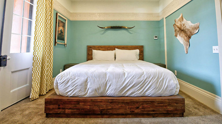 The Adobe Suite features a king bed set in reclaimed wood, an 1849 original French door, an oversize bathroom with a rain shower and direct access to the wraparound porch.