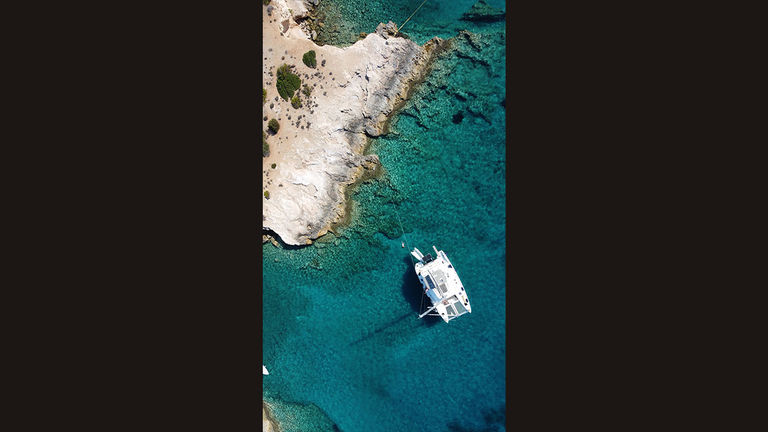 Sunbathing in the Greek isles next to a catamaran