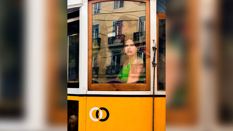 The third-place winning photo depicts a woman in a Lisbon tram.