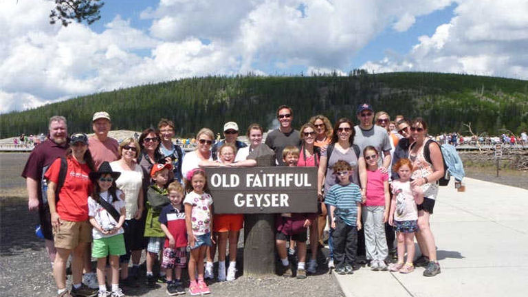 The group poses for a photo at Old Faithful Geyser in Yellowstone National Park. // © 2013 Adventures by Disney