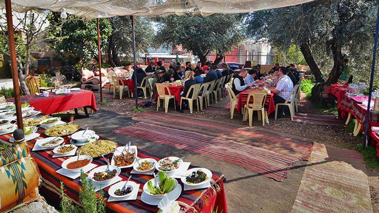 Visitors enjoy lunch under the trees at Bait Khayrat Souf. // © 2018 Tourism Cares