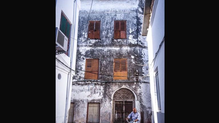 A Zanzibari man rides his bicycle through Stone Town. // (c) 2013 Bob Demyan