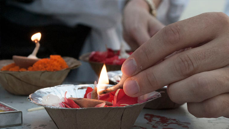 As the sun rises, it is customary to make a wish while releasing a diya into the water. // © 2014 Mindy Poder