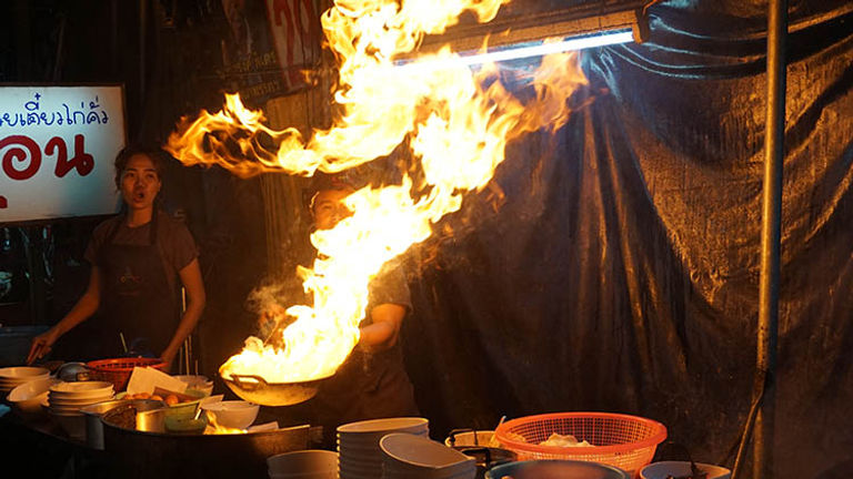 Frying rice noodles, or kuay teow kua gai, in a sizzling wok may result in a fire show for passersby. // © 2017 Valerie Chen