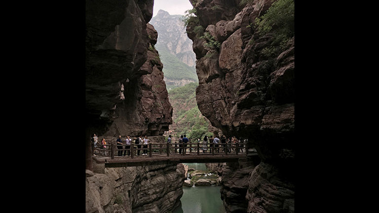 Travelers will find views of tall, jagged peaks and brilliantly colored water as they walk along the pathway cut into the rock. // © Michelle Juergen