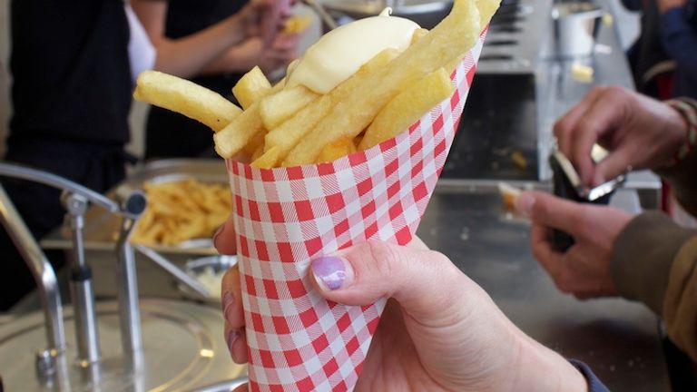 Another snack often eaten on the go are frites, served in a paper cone and topped with mayonnaise. // © 2014 David Wade