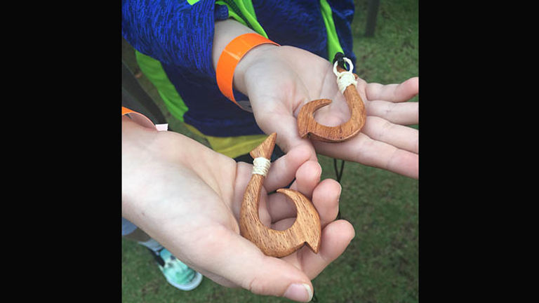 Kids receive wooden Maui fishhook necklaces. // © 2017 Samantha Davis-Friedman
