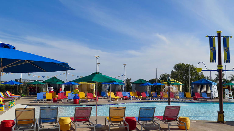 The colorful pool area has floating Lego bricks and water features.
